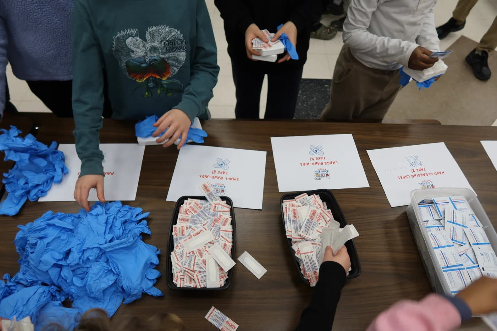 Students assembling care kits at cafeteria tables