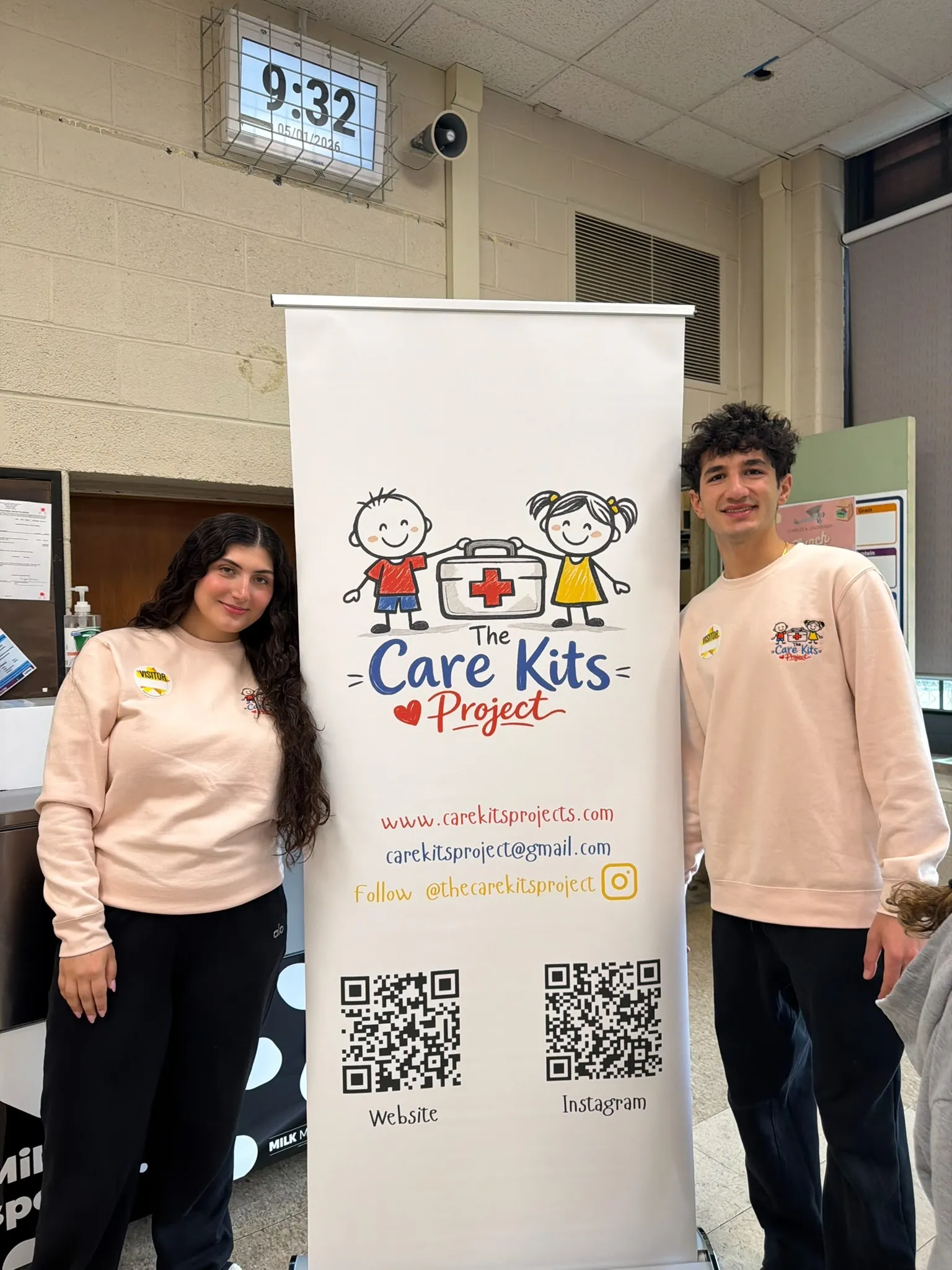 Lilyana and Alexander standing with the Care Kits Project banner at a school workshop