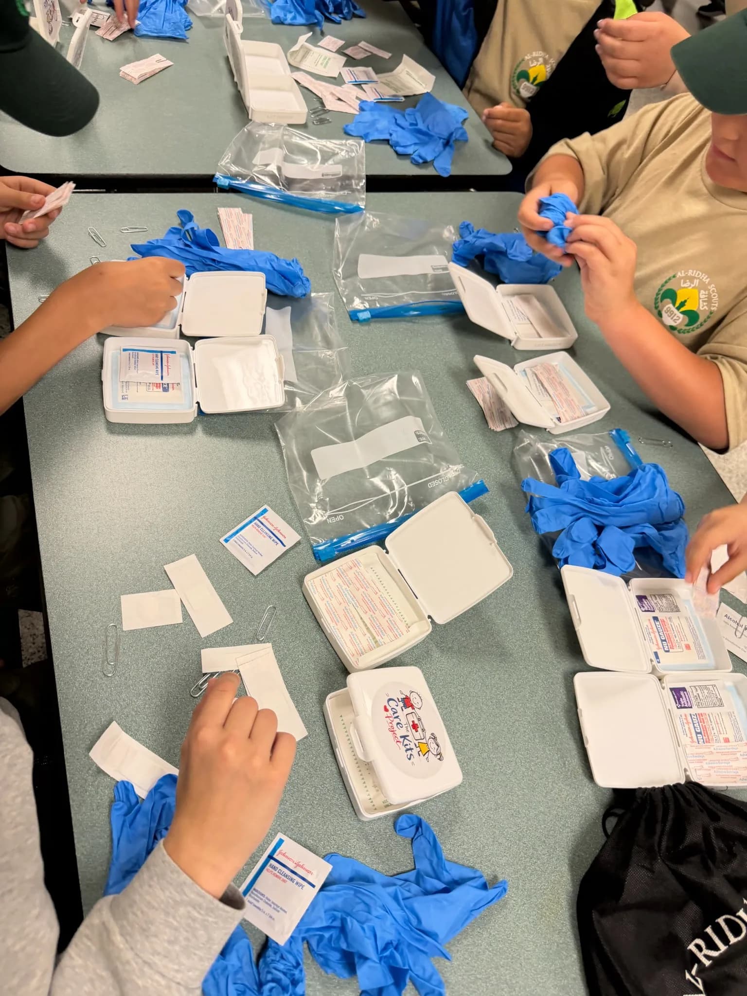 Scouts assembling care kits, with gloves, bandages and kit cases spread across the table